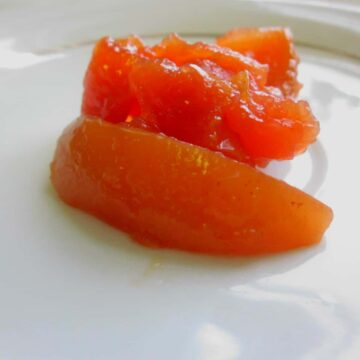 A plate of quince preserves on a white surface.