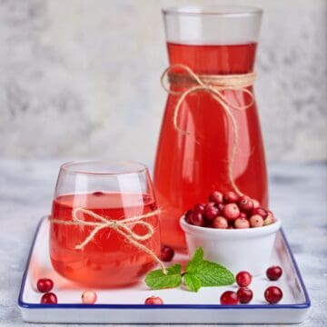 Cranberry mors in a pitcher and glasses on a tray.