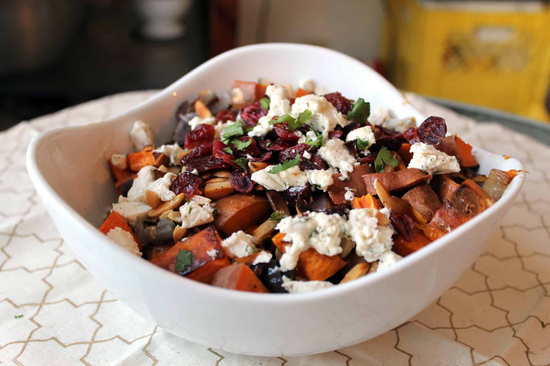 Roasted sweet potato salad with onions, cranberries and nuts served in a white bowl