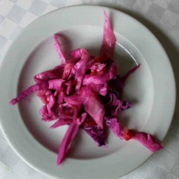 A plate of quick-pickled red cabbage on a white tablecloth.