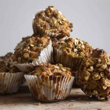 A stack of morning glory muffins on a wooden cutting board.