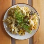 A plate of pasta with mushrooms and a sprig of dill.