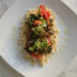Plate of roasted swiss chard and tomatoes on rice, on a white tablecloth
