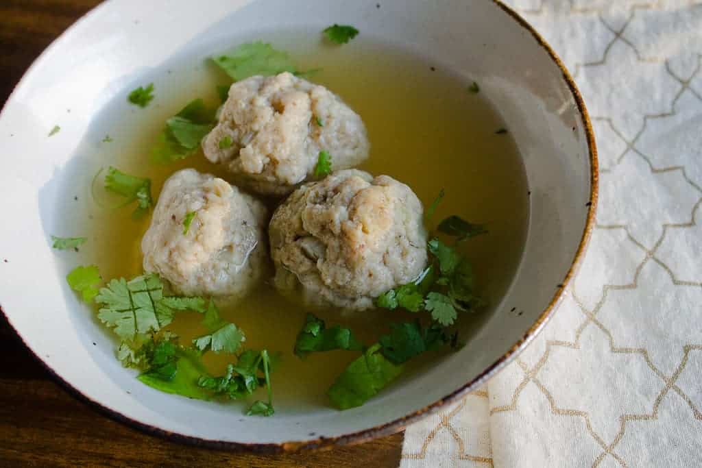 Finished matzo balls in soup garnished with parsley.