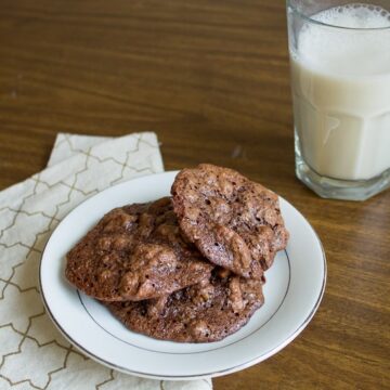 Gluten-free chocolate chip cookies on a plate next to a glass of milk.