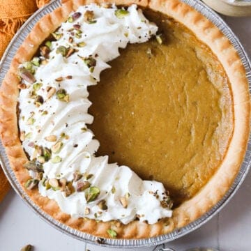 Hubbard squash pie with whipped cream and chopped pistachios on top, arranged in a crescent shape.
