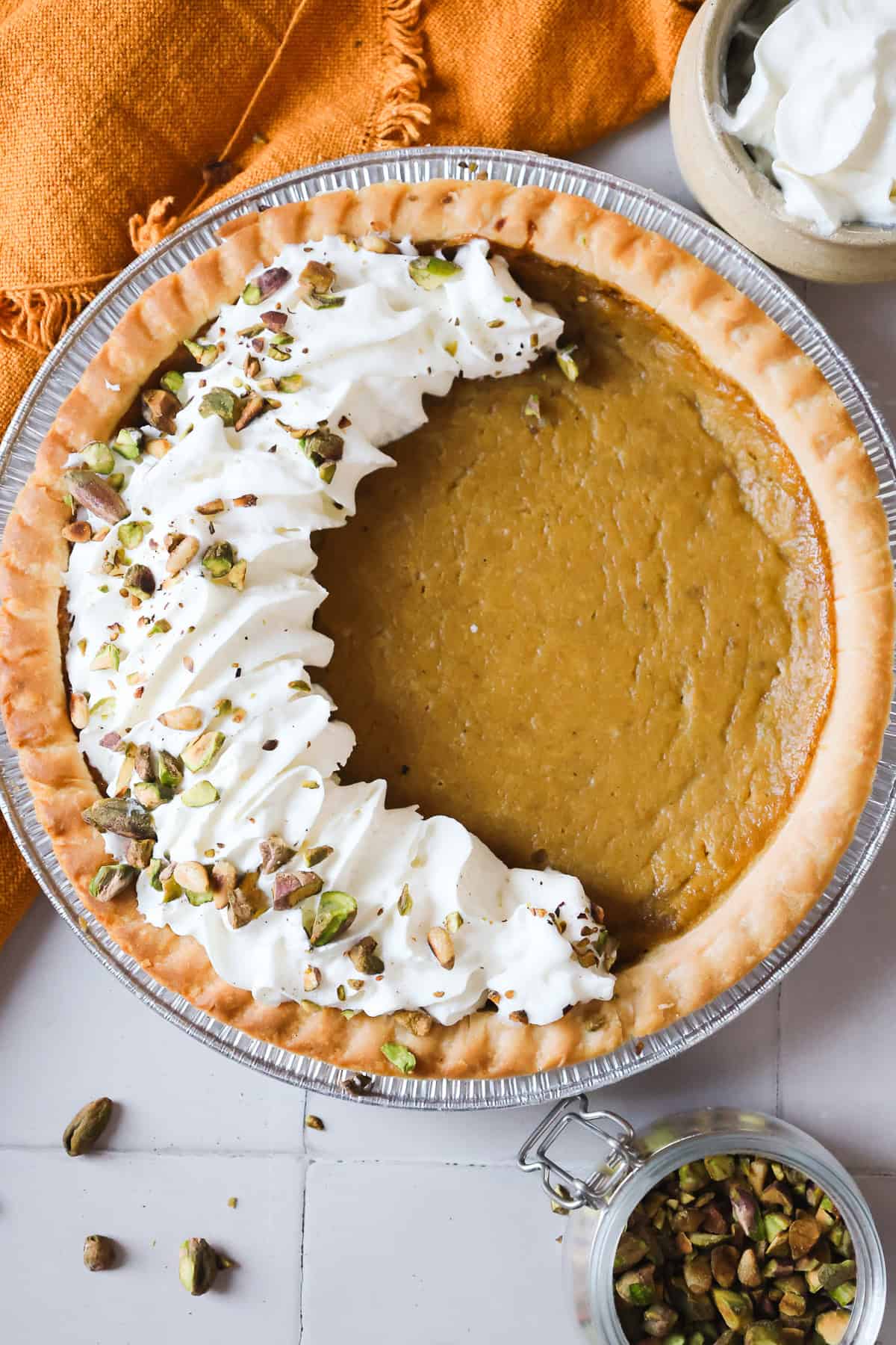 Hubbard squash pie with whipped cream and chopped pistachios on top, arranged in a crescent shape.