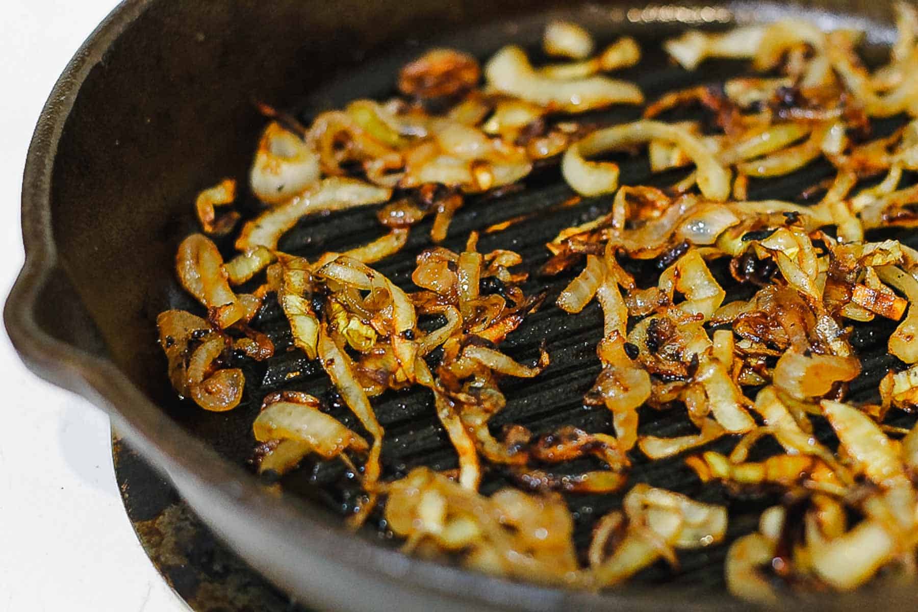 A frying pan with onions and puff pastry pockets.