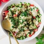 Israeli salad in white bowl with gold spoon.