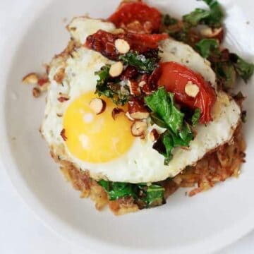 Breakfast potato latkes topped with egg, kale, tomatoes and Tamari almonds