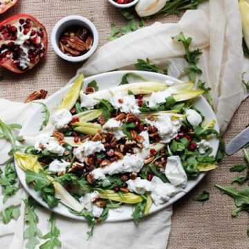 Endive and arugula provide the peppery bite to this arugula salad, while the milky fresh mozzarella brings creaminess, & the pomegranate and pecans the pop.