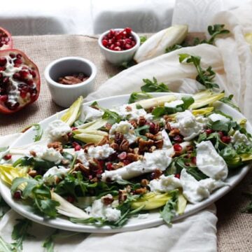 Endive and arugula provide the peppery bite to this arugula salad, while the milky fresh mozzarella brings creaminess, & the pomegranate and pecans the pop.