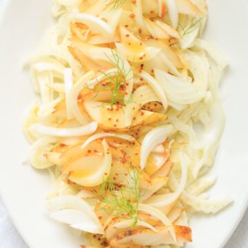 A white plate with onions and fennel on it.