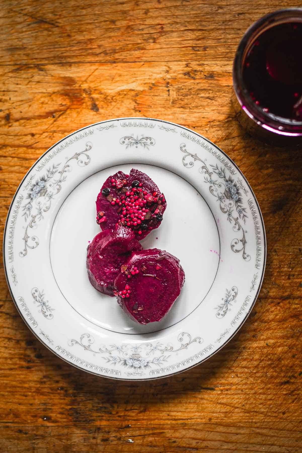 Overhead view of pickled beets on plate beside jar.