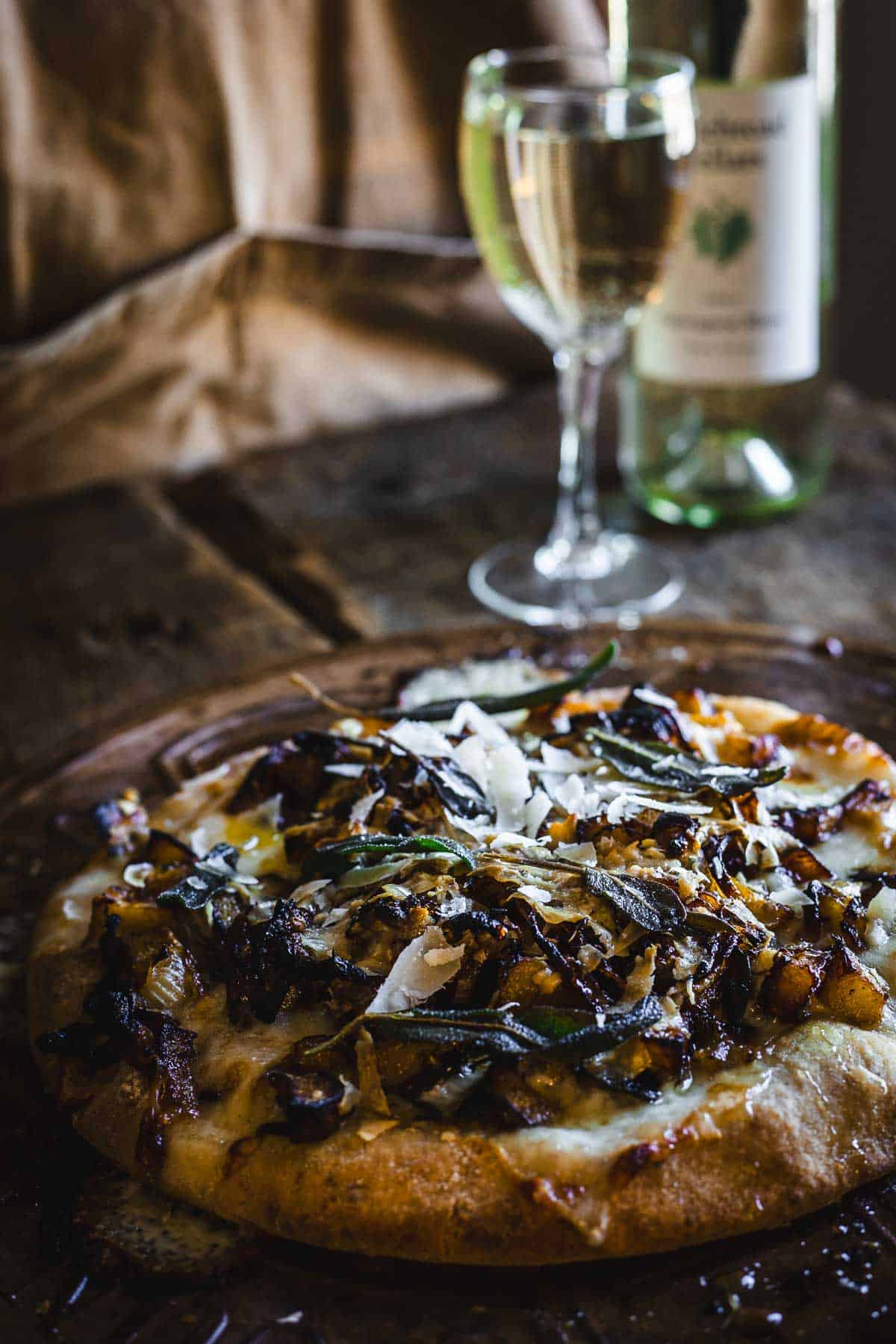 A pizza topped with garlic is sitting on a table next to a glass of wine.