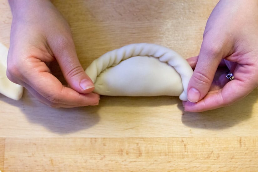 hands crimping empanada