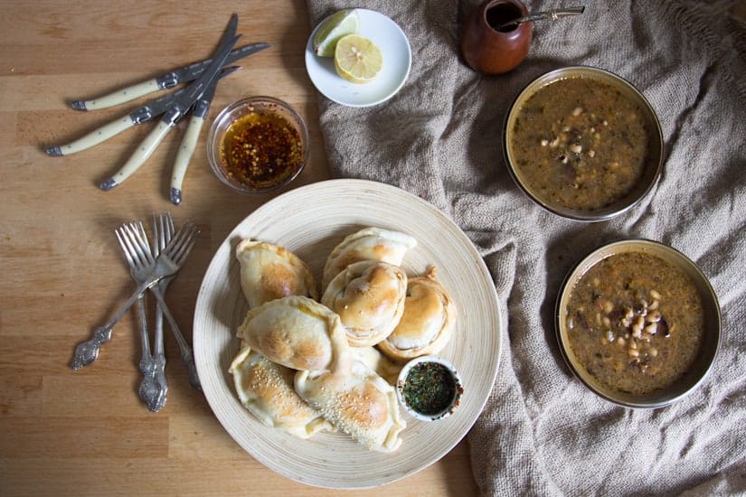 empanadas on plate with cutlery and soups