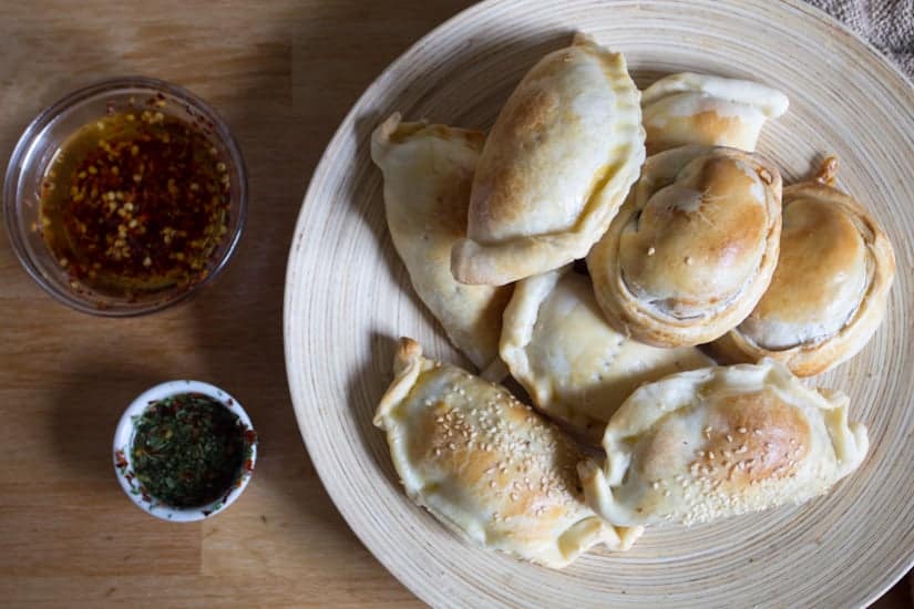 empanadas on a plate with dipping sauces