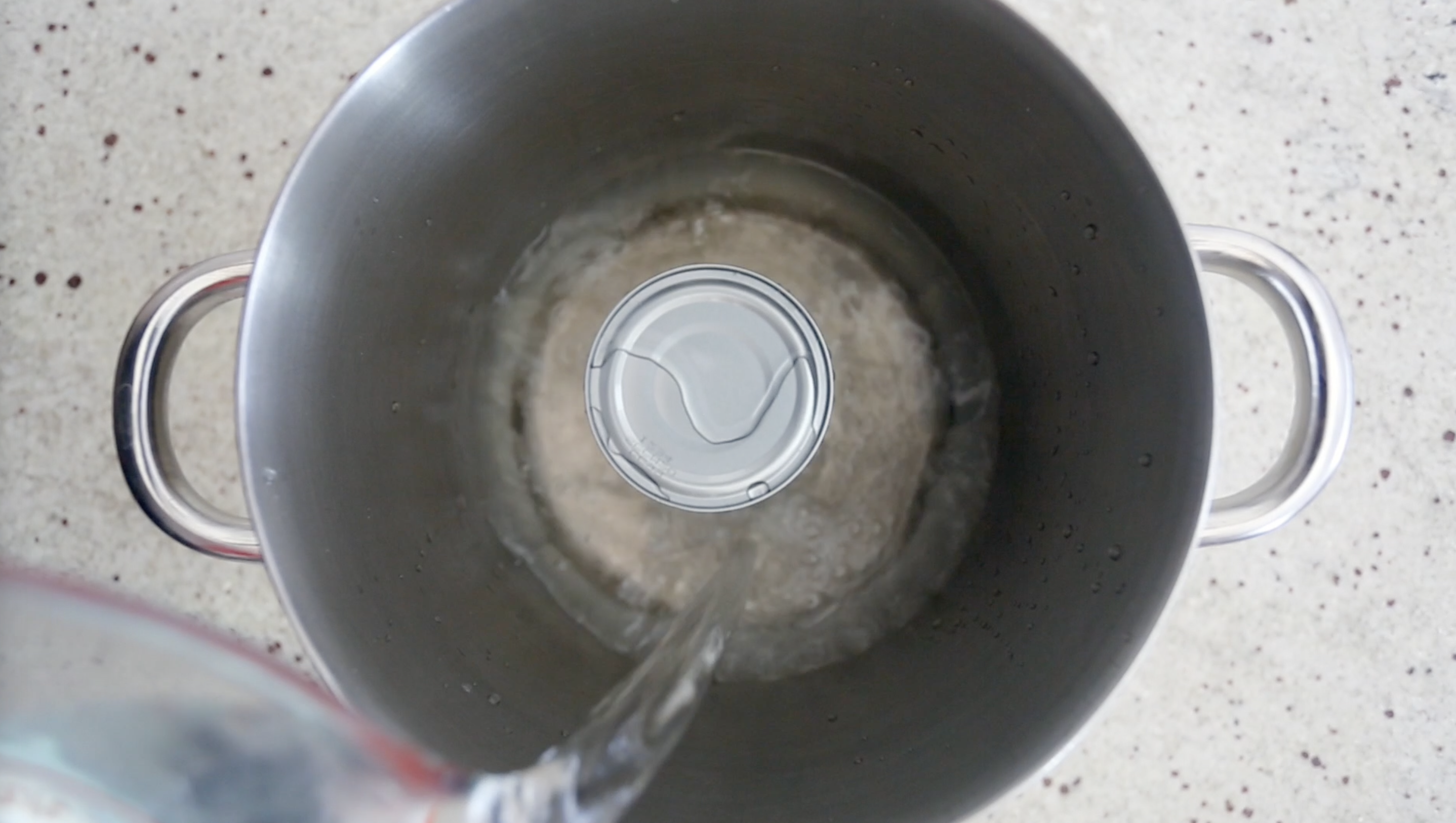 pouring water with can of coconut milk in pot