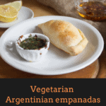 Argentinian empanada on a plate with chimichurri dipping sauce and more empanadas in the background