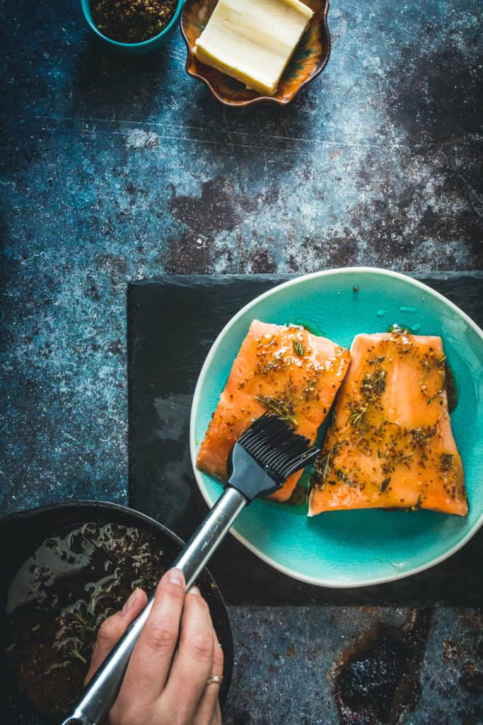 Sockeye salmon being brushed with butter and herbs