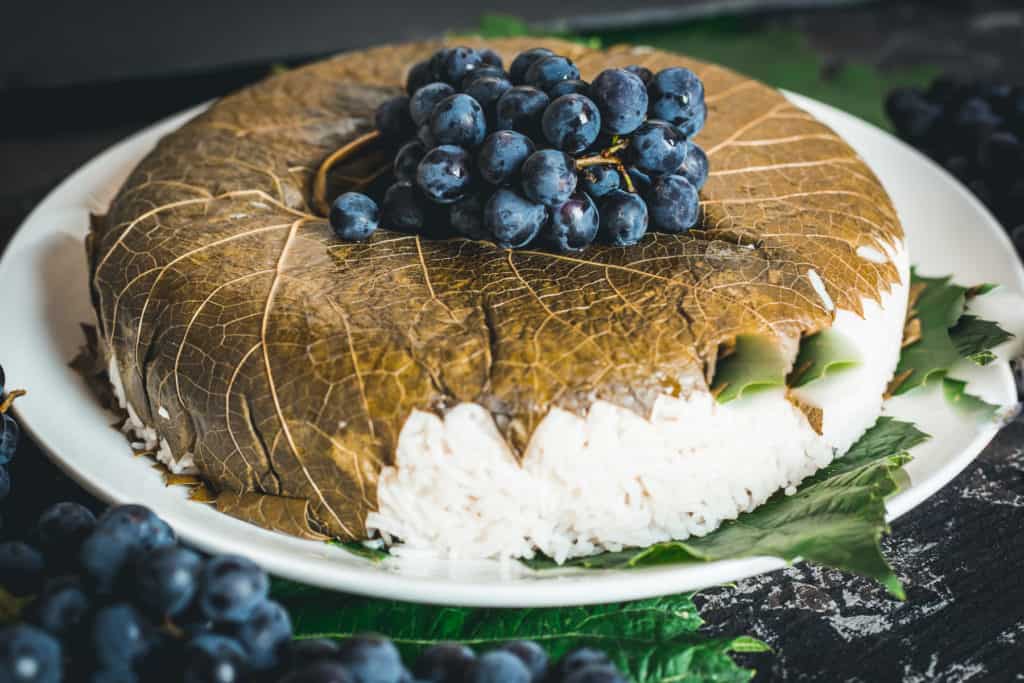 Side view of rice topped with grape leaf and fresh grapes