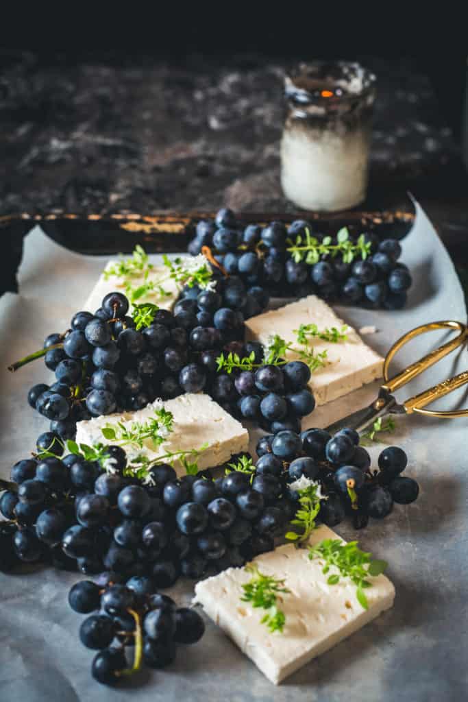 Tray with fresh feta and grapes, scissors and candle