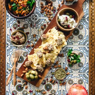 A Middle Eastern appetizer platter showcasing a variety of foods on a wooden platter.