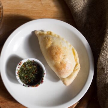 vegetarian empanada on a plate with chimichurri dipping sauce  Apple olive oil cake Argentinian Empanadas THUMBNAIL 360x360