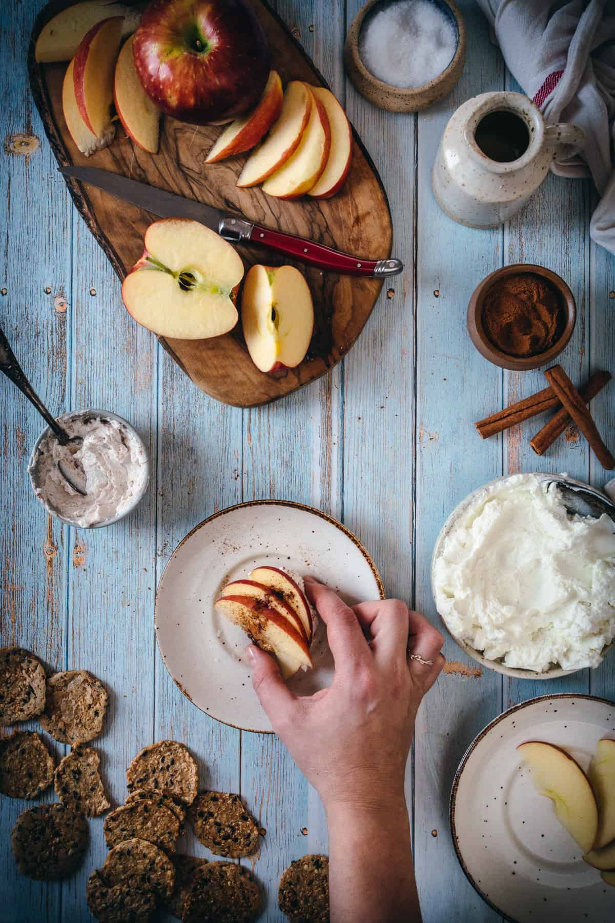 hand grabbing apple labaneh cracker