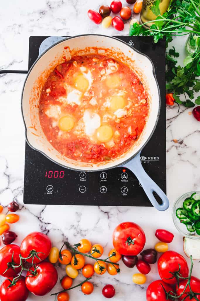 adding eggs to shakshuka