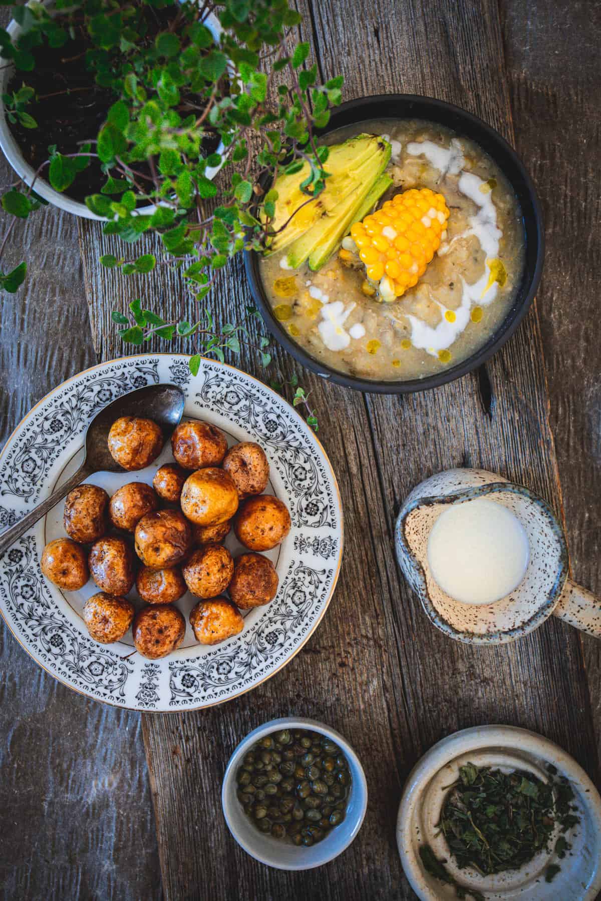 ajiaco bowl with cream, papas criollas and oregano plant