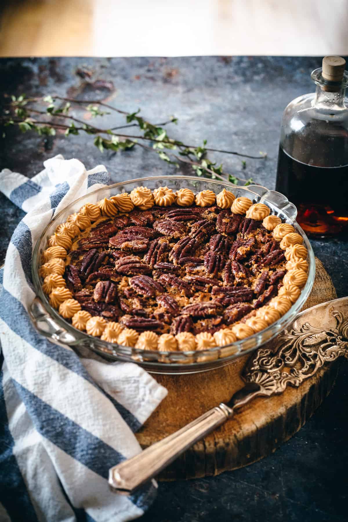 baked gluten free pecan pie decorated with maple syrup bottle