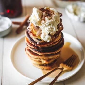 A stack of low carb pancakes with whipped cream and cinnamon.