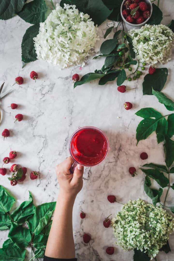 hand holding cup of raspberry sauce