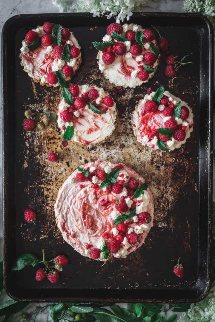 overhead of one large and four individual raspberry cheesecakes on baking sheet