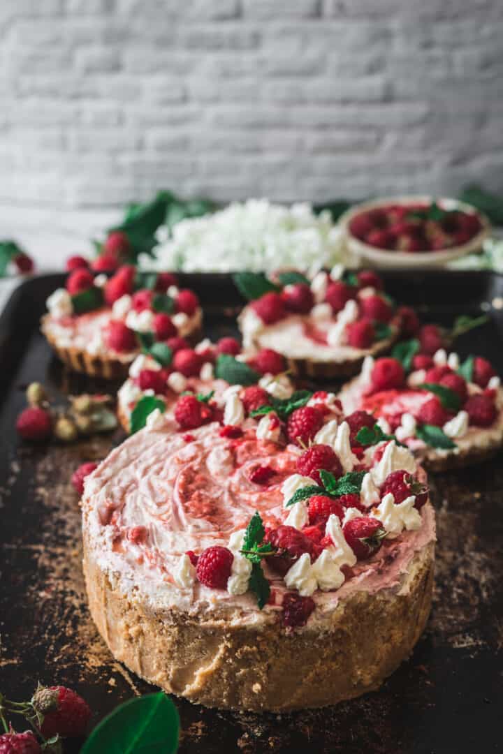 close up of one large and four individual raspberry cheesecakes on baking sheet