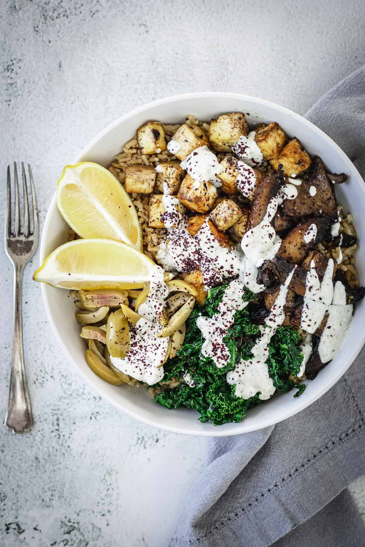 overhead view of middle eastern tofu and rice bowl with napkin and fork