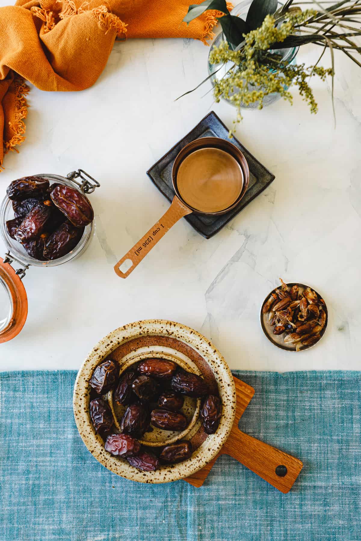 dates in a plate, water in a measuring cup, and dates in a jar