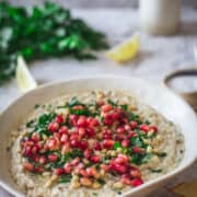 hand lifting piece with Lebanese Baba Ganoush recipe with pomegranate seeds and pine nuts