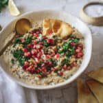 Lebanese Baba Ganoush recipe with pomegranate seeds and pine nuts with a spoon and pita triangle