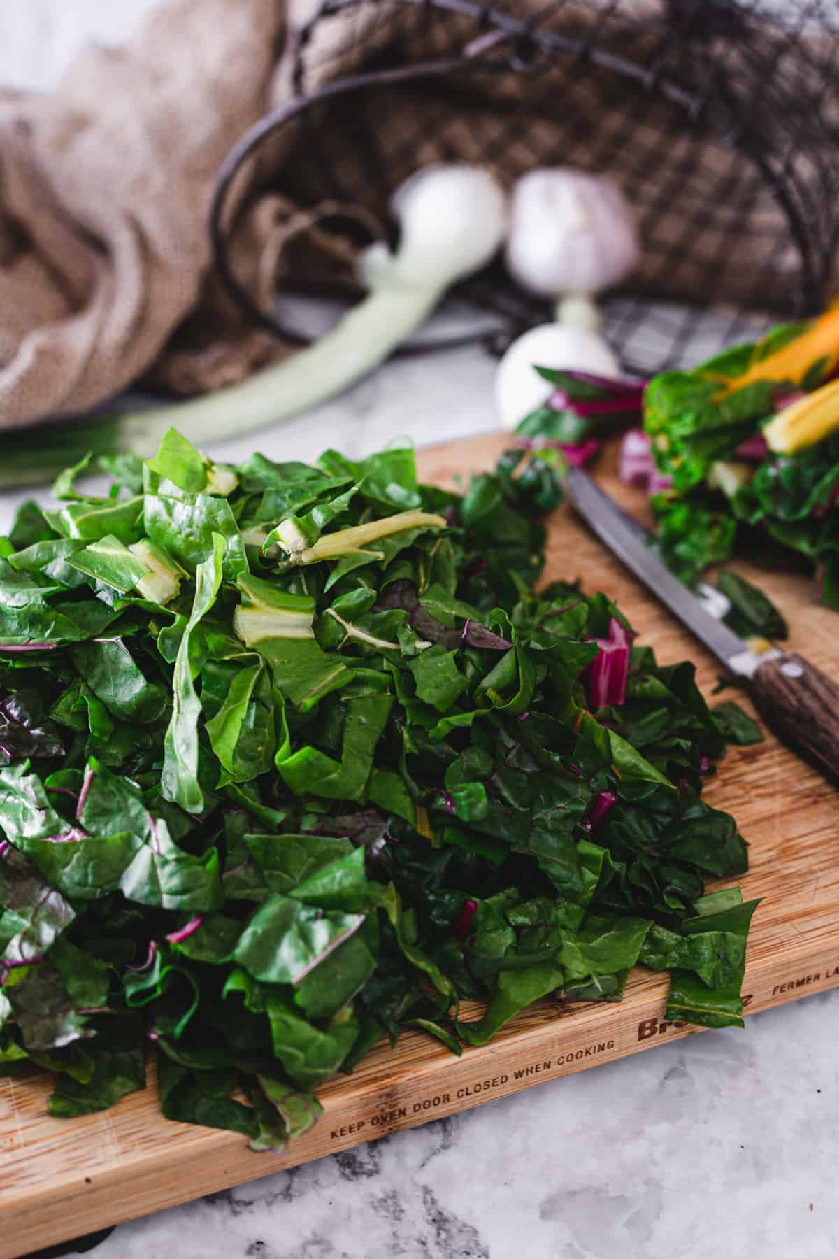 rainbow chard leaves on a cutting board with a knife