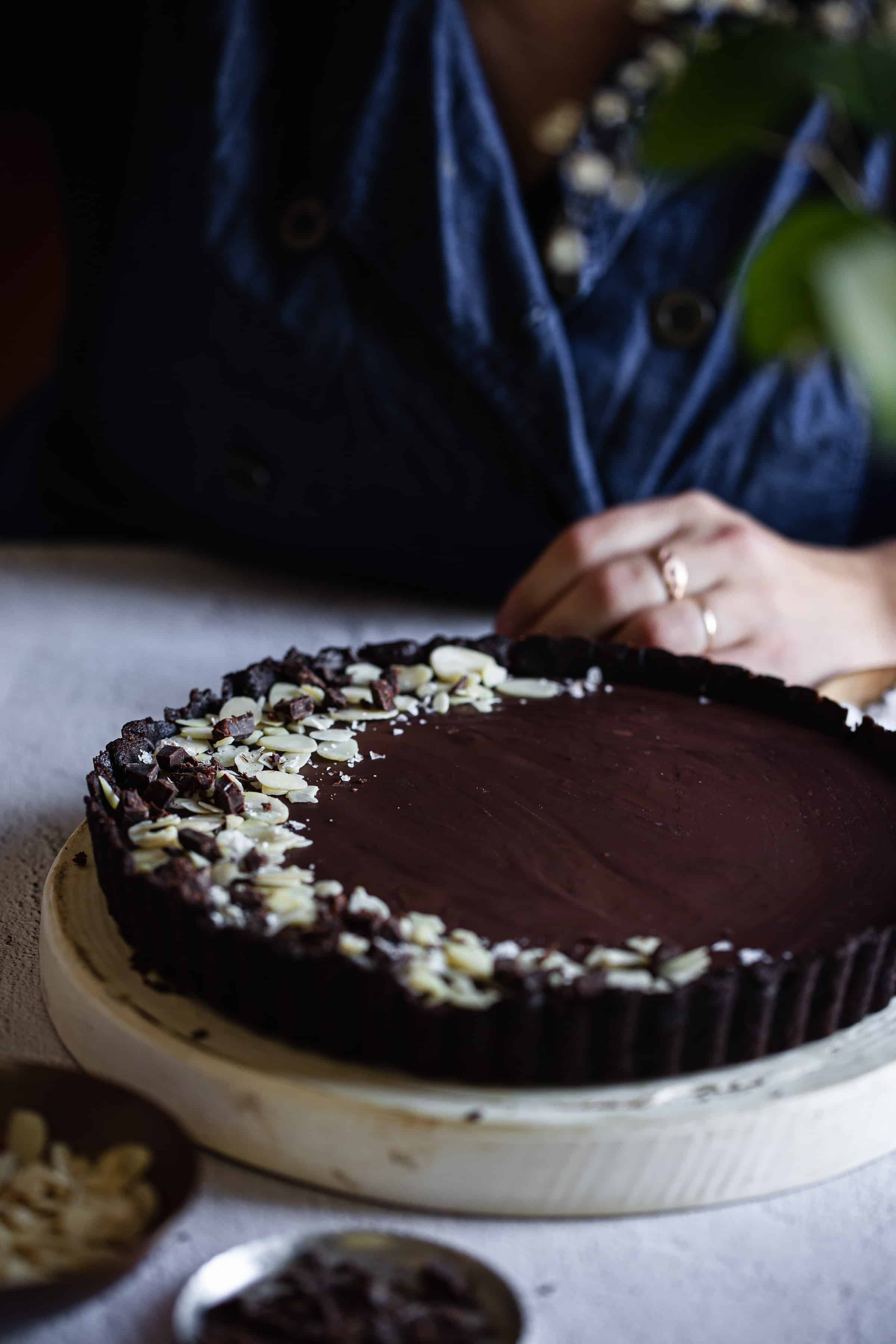 side view of chocolate tart on table with person in background