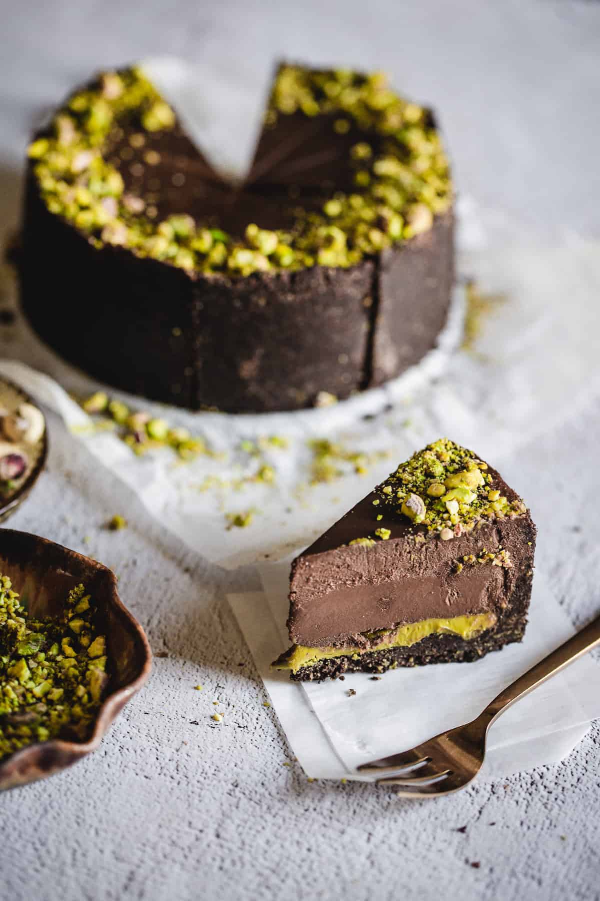one slice and fork in front of chocolate pistachio cake