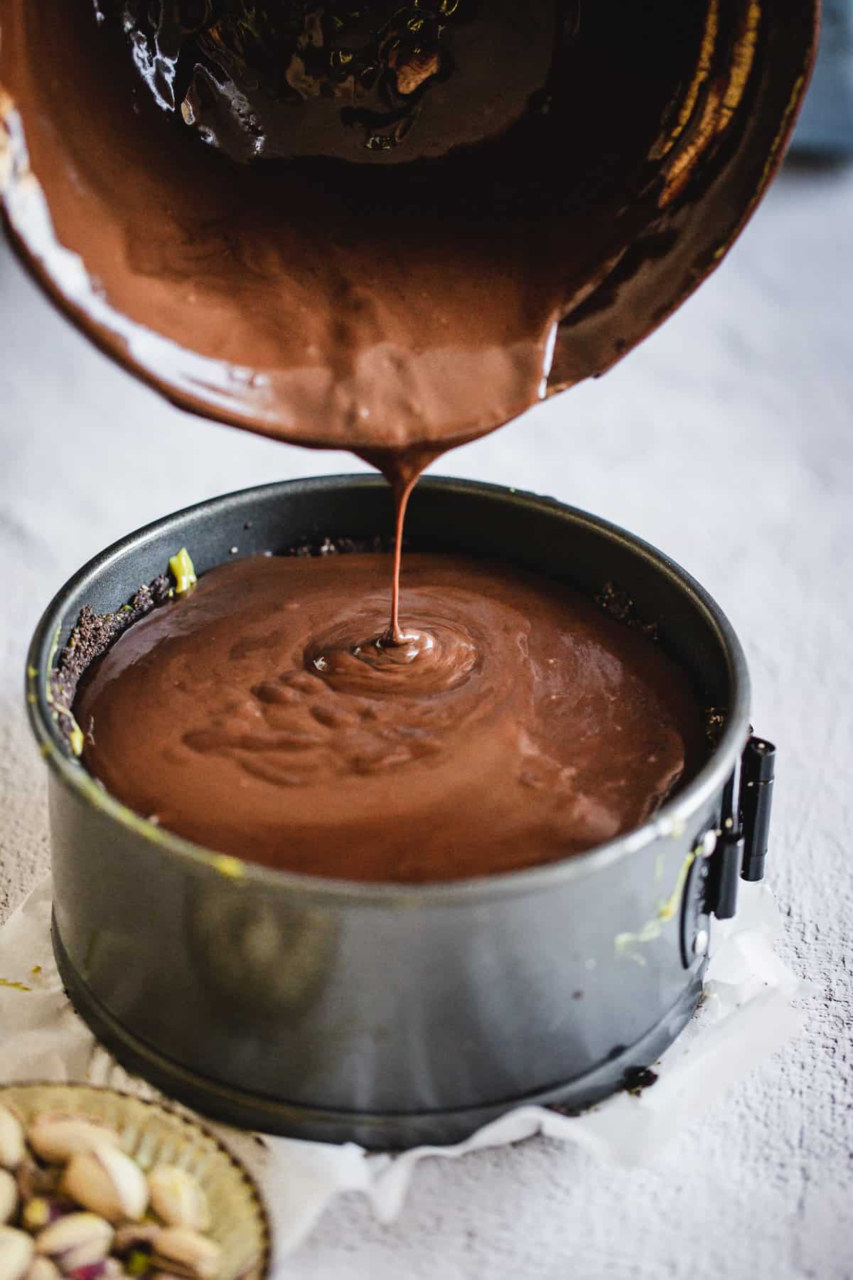 pouring chocolate ganache into cake