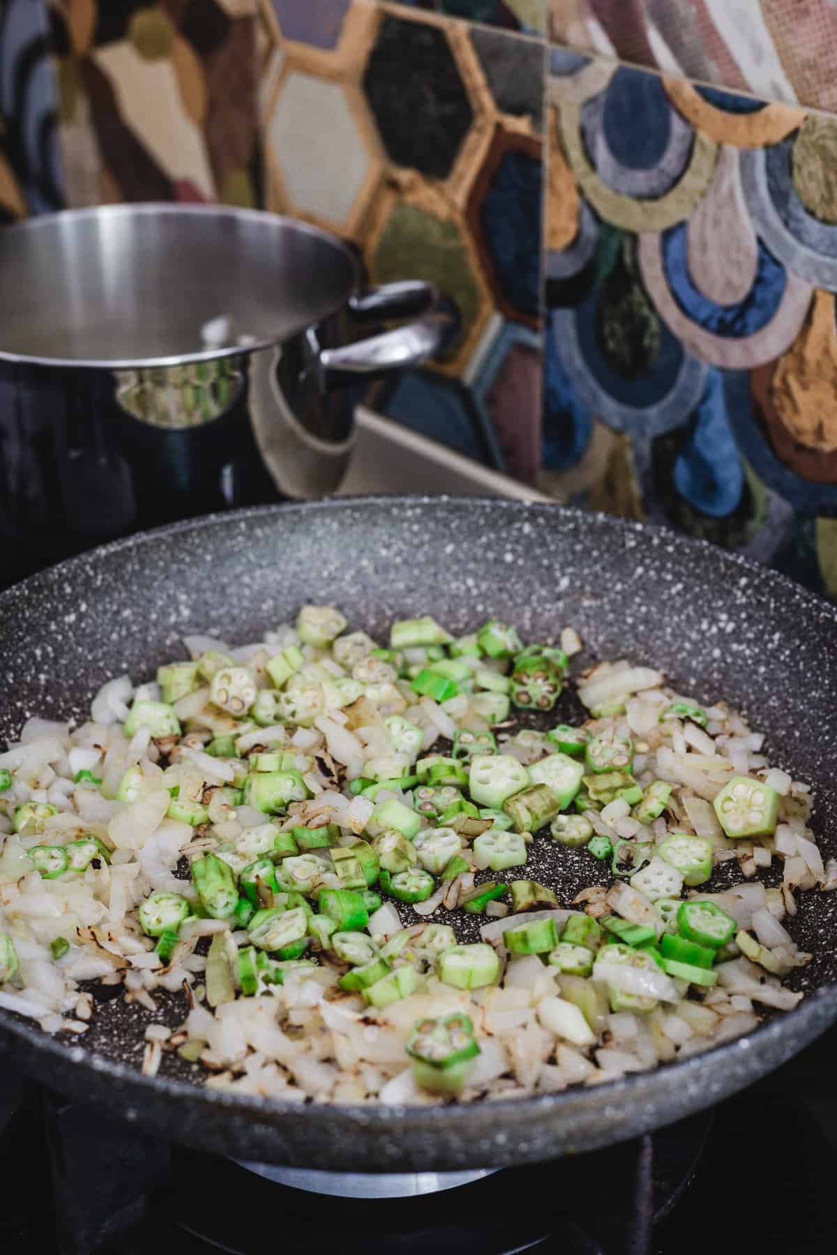 Frying okra and onions in pan