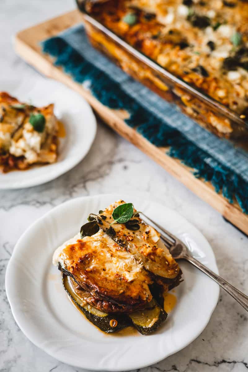 two plates of vegetarian moussaka with moussaka pan in the background