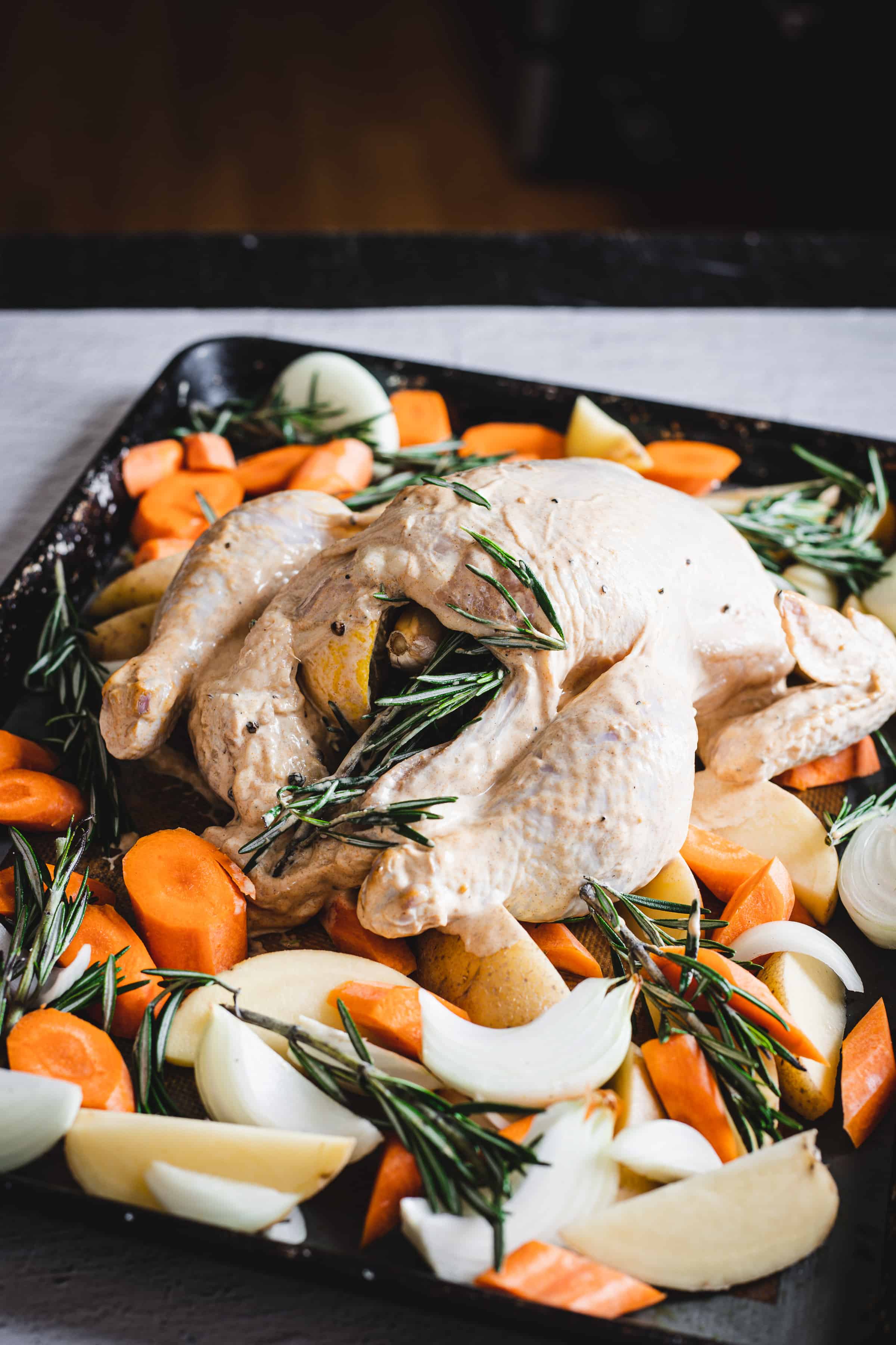 an overhead view of chicken stuffed with lemon and rosemary surrounded by veggies with rosemary