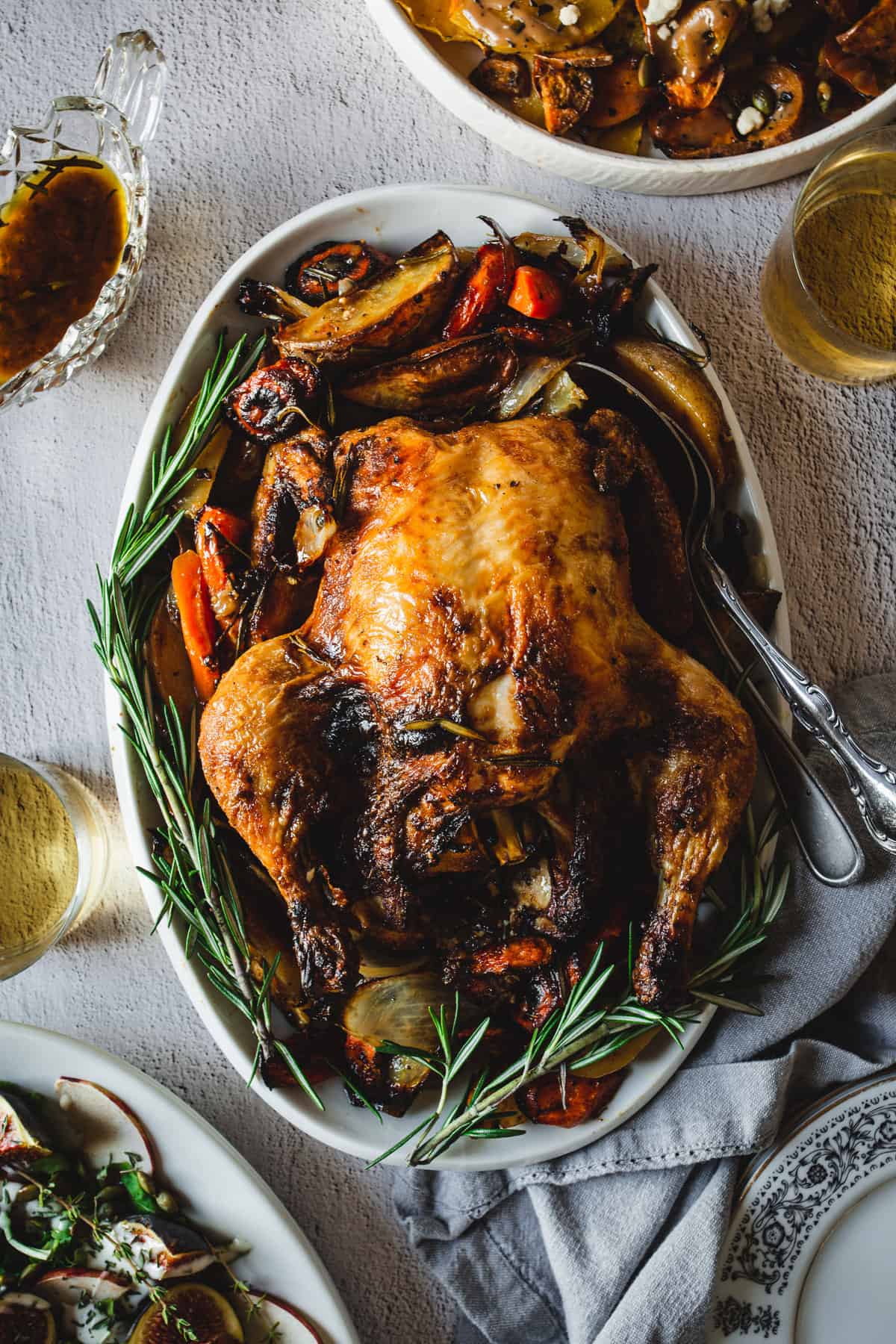 overhead view of paprika chicken surrounded by roasted vegetables and side dishes and sauce