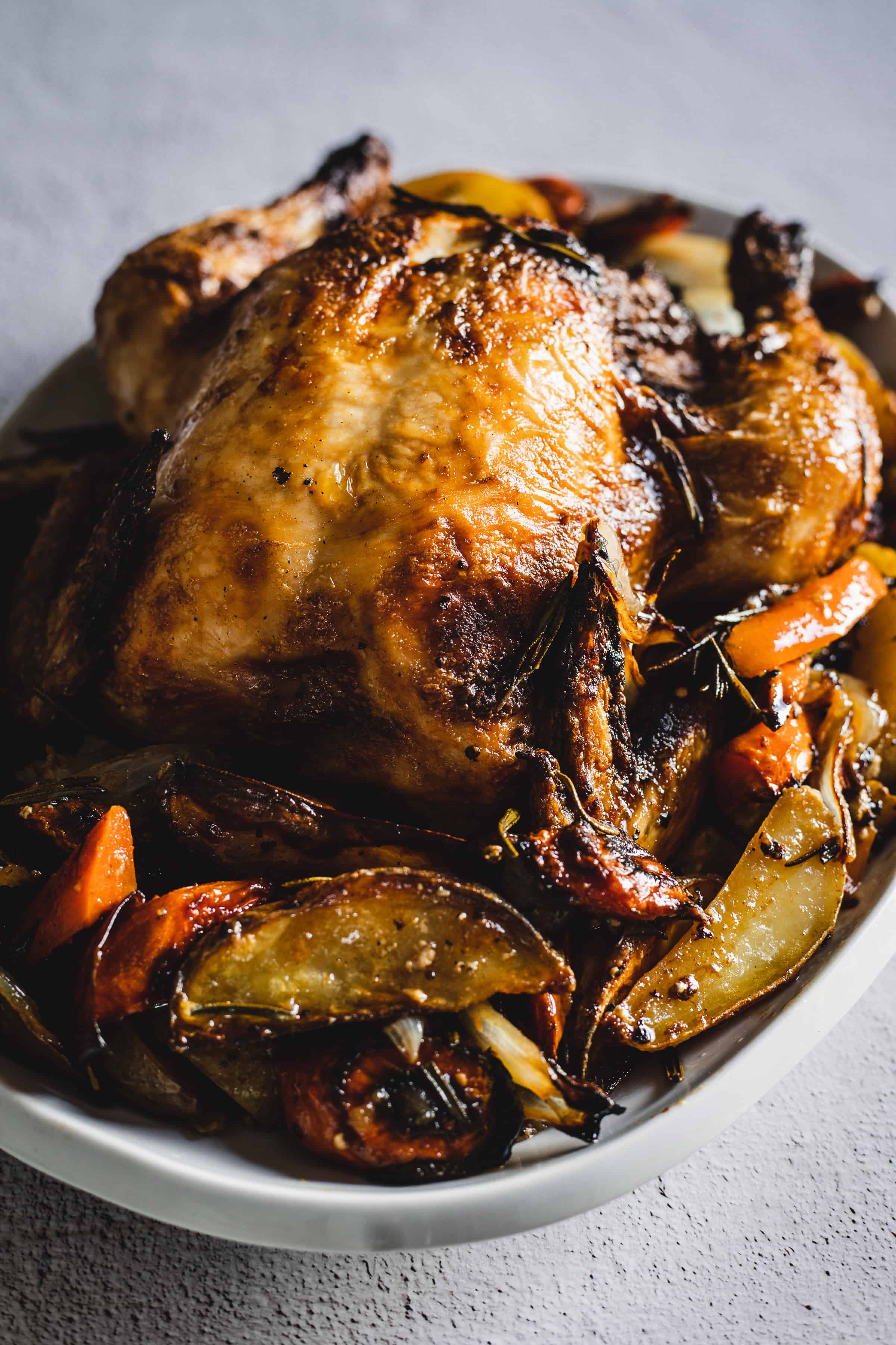 whole roasted chicken surrounded by roasted veggies